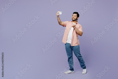 Canvas Print Full body young Indian man he wear pink shirt white t-shirt casual clothes doing selfie shot on mobile cell phone post photo on social network isolated on plain pastel light purple background studio