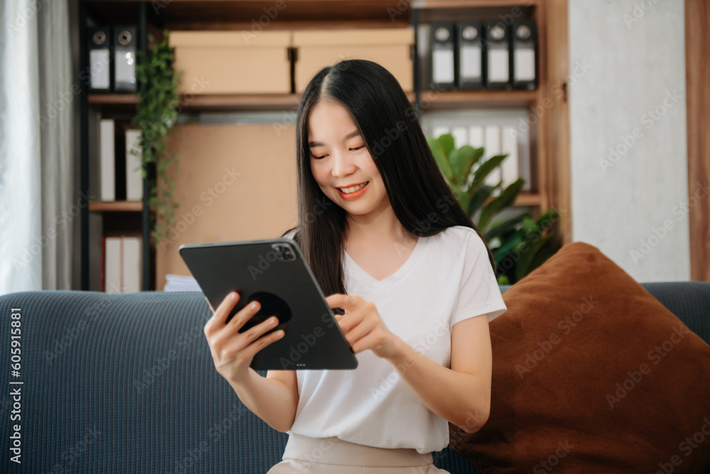 Asian woman using the smartphone and tablet on the sofa at home. Asian woman using the smartphone and tablet on the sofa at home.