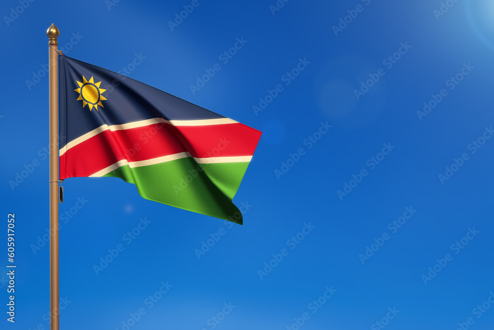 Naklejka premium Namibia. Flag blown by the wind with blue sky in the background.
