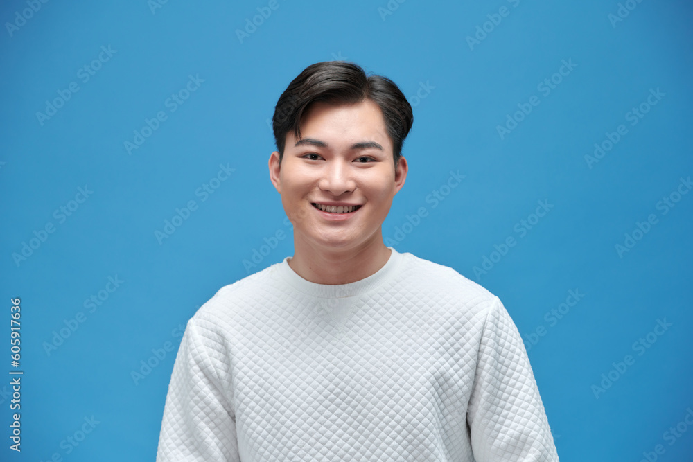 Fototapeta premium Portrait of good looking asian man over blue background.