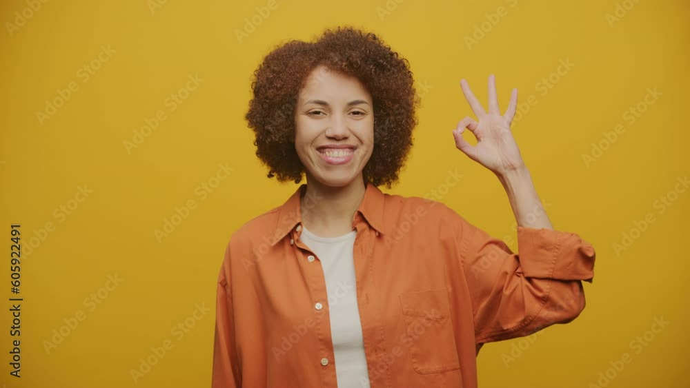 Woman Showing OK Sign or Gesture on Yellow Background Woman Showing OK Sign or Gesture on Yellow Background