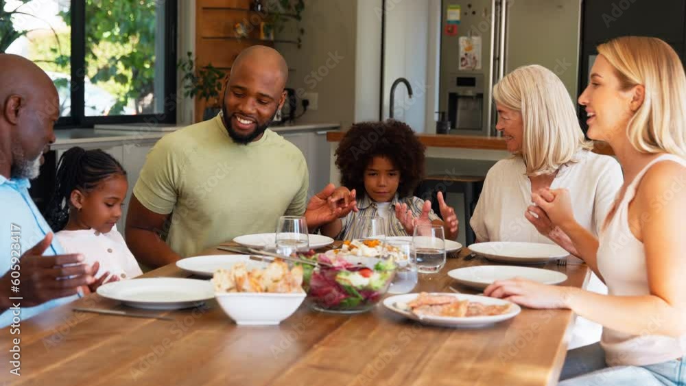Multi-generation family sitting at table holding hands and saying prayer before meal at home -shot in slow motion Multi-generation family sitting at table holding hands and saying prayer before meal at home -shot in slow motion