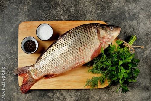 Fresh raw river carp on a cutting board with parsley, sea salt and pepper photo