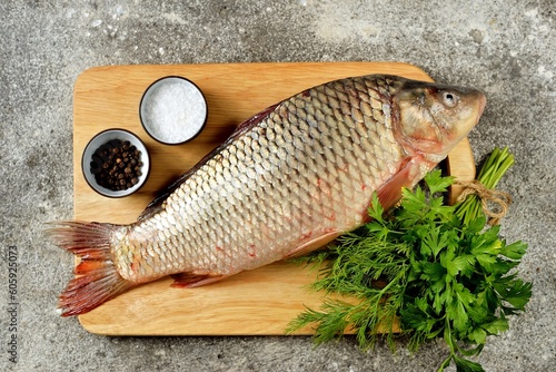 Fresh raw river carp on a cutting board with parsley, sea salt and pepper