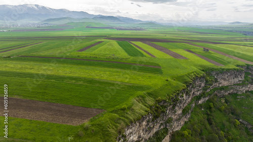 panoramic view of the gorge with a river and green fields on a plateau against the backdrop of the mountains of Armenia view from a drone