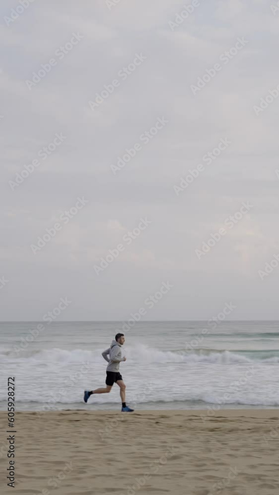 Young sportsman running at the beach. Man doing exercise outdoors Young sportsman running at the beach. Man doing exercise outdoors