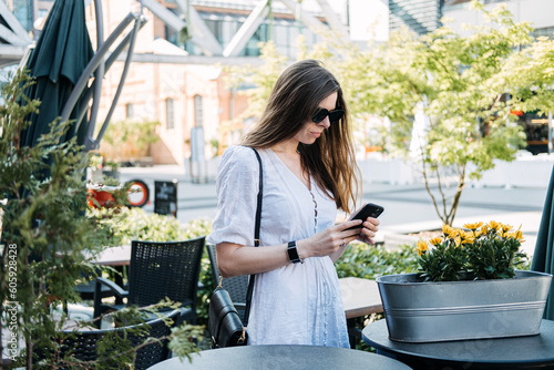 FOMO, Fear of missing out, social anxiety, stay continually connected, fear of regret, Social networking. Woman Checking her Smartphone and reading messengers and Social media outdoors photo