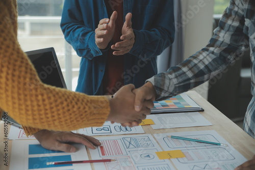 Close up ux developer and ui designer brainstorming about mobile app interface wireframe design on table with customer breif and color code at modern office.Creative digital development agency photo