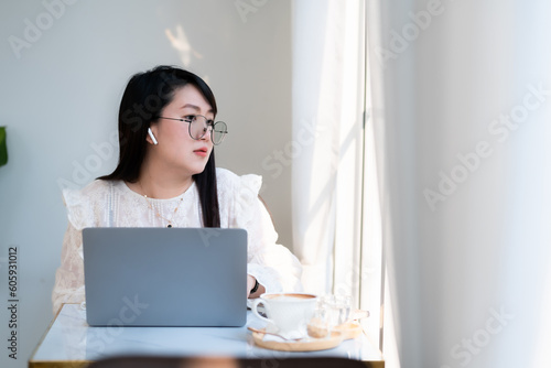 Happy of asian freelance people Businesswoman wearing wireless earphones casual working with laptop computer with a coffee cup mug,Notebook and smartphone at the cafe,Business Lifestyle communication