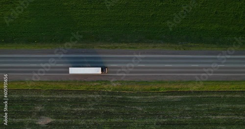 A truck with a semi-trailer is driving along a straight highway, aerial view. Truck traffic on the freeway, top view. Cargo transport.
