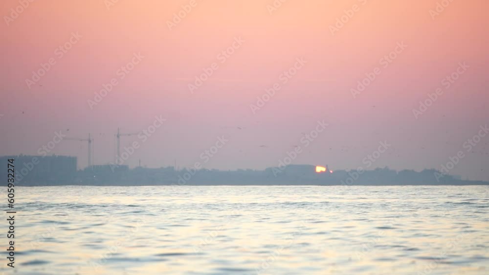 Sunset sea and silhouette of resort town located on the seashore with red sunset sun behind. Holiday recreation concept. Abstract nautical summer ocean sunset nature background. Sunset sea and silhouette of resort town located on the seashore with red sunset sun behind. Holiday recreation concept. Abstract nautical summer ocean sunset nature background.