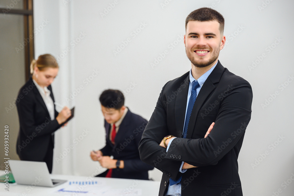 Portrait of business owner or young businessman smiling looking at camera. In meeting room. Handsome businessman manager smiling confidently standing in office at team meeting. Portrait of business owner or young businessman smiling looking at camera. In meeting room. Handsome businessman manager smiling confidently standing in office at team meeting.