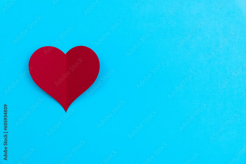 Red paper heart on blue background