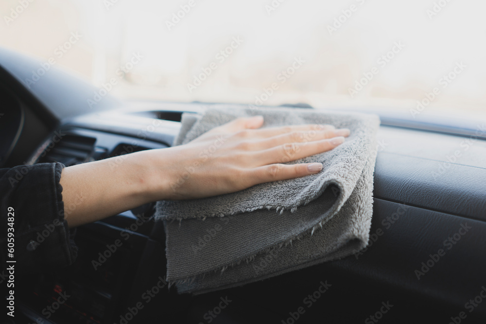 female driver is wiping a car interior using microfiber