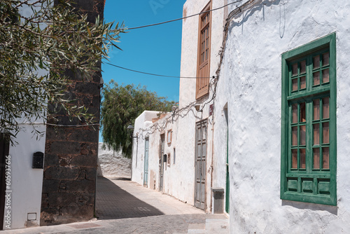 Typical Canary Islands street with white houses, green wooden doors and windows and colorful flowers in Teguise village, Canary Islands, Spain.