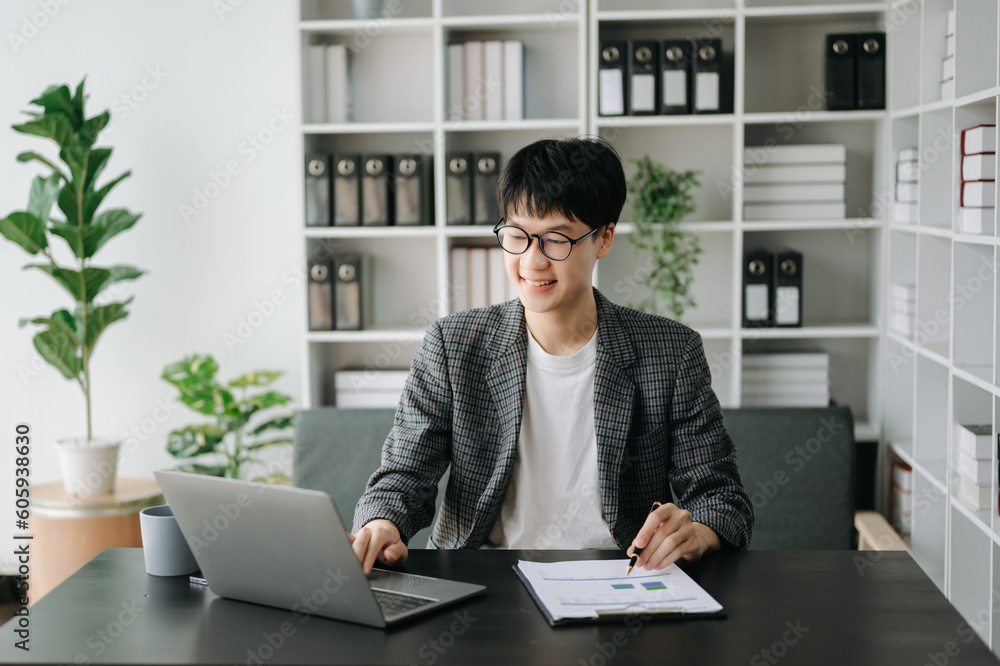 Young business man working at modern office with laptop, tablet and taking notes on the paper.. Young business man working at modern office with laptop, tablet and taking notes on the paper..