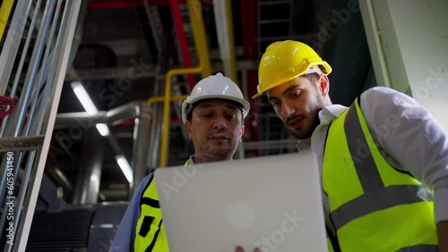 Two professional electrical engineer in safety uniform working together at factory site control room. Industrial engineer worker checking maintenance electric system on laptop computer at plant room.