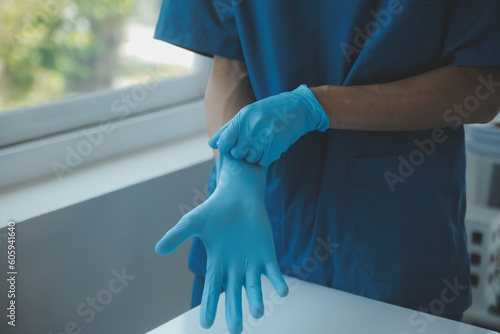 Doctor or nurse putting on blue nitrile surgical gloves, professional medical safety and hygiene for surgery and medical exam on white background. photo
