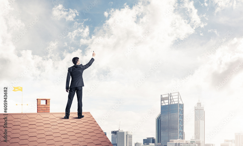 Businessman on house roof touch empty space. Mixed media Businessman on house roof touch empty space. Mixed media