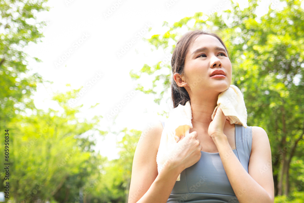 Asian woman exercising outdoors on a hot sunny day with her body temperature above 40 degrees Celsius. She wipes her sweat with a towel. heat stroke concept. copy space Asian woman exercising outdoors on a hot sunny day with her body temperature above 40 degrees Celsius. She wipes her sweat with a towel. heat stroke concept. copy space