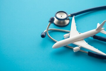 Airplane and stethoscope on blue background with copy space. Going abroad for medical care. Medical tourism is when a person travels to another country for medical care. Healthcare, travel concept.