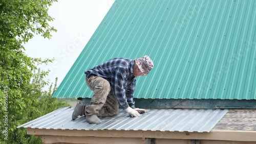 Wallpaper Mural skilled senior builder sits on roof, using a power drill to install metal shingles, depicting architectural journey of retiree. lifelong learning, and fulfillment of personal projects in retirement. Torontodigital.ca
