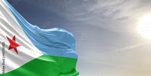 Djibouti national flag cloth fabric waving on beautiful grey sky Background. photo