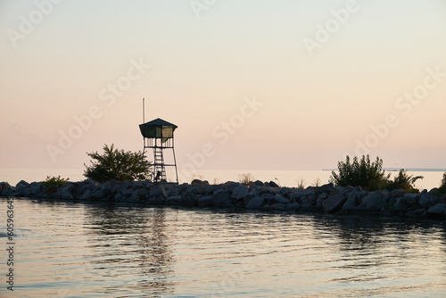 Nikopol, Dnipropetrovsk, Ukraine - 03-30-2021: Silhouette of an old rescue booth on a rocky pier. Evening on the beach. Pastel sunset. photo