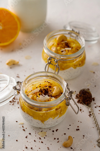Chia seed pudding with orange puree, chocolate and cashew in glass jar. Closeup view. Vegan vegetarian food, clean eating concept