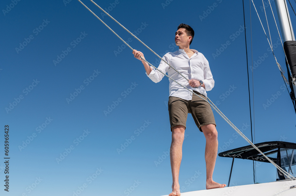 From below of concentrated male standing on deck of catamaran while pulling ropes and setting sail From below of concentrated male standing on deck of catamaran while pulling ropes and setting sail