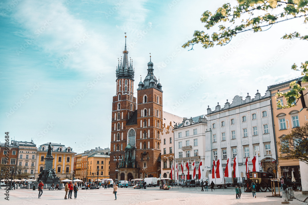 Old city center view with Adam Mickiewicz monument, St. Mary's Basilica and birds flying in Krakow on the morning. High quality photo