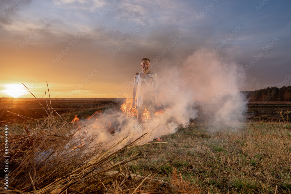 Fototapeta premium young guy crying in fire in burnt clothes, war, home destruction, human disappointment