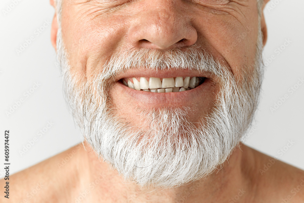 Fototapeta premium Cropped close-up image of grey-haired man's beard. Mature male model smiling against grey background. Dental teeth care. Concept of male beauty, face and skin care, daily procedures, age