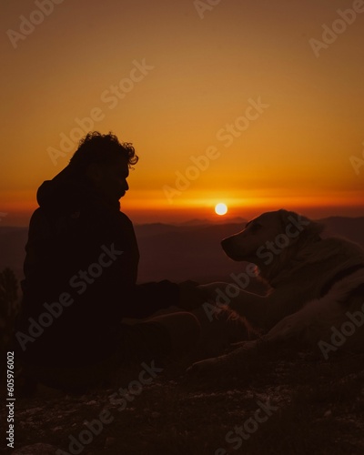Guy and a dog with sunset landscape on the background