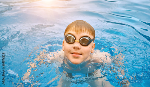Smiling boy portrait in swimming goggles, Child swim in the pool, sunbathes, swimming in hot summer day. Relax, Travel, Holidays, Freedom concept.
