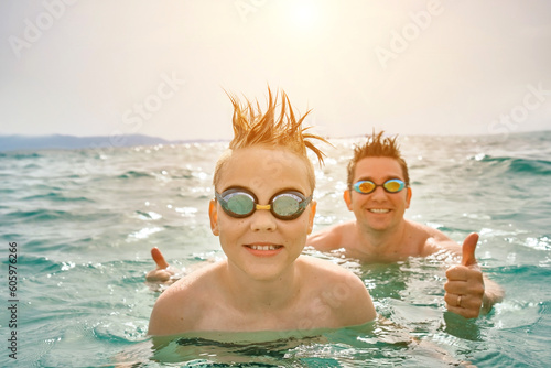 Happy family in swim outdoors, father and son bonding, play, swim in the sea looking at view enjoying summer vacation. Togetherness Friendly concept 