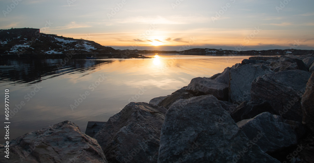 Fabulous sunset over the rocky shore of the North Sea in Norway. Sunny path in cool, calm water