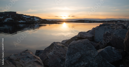 Fabulous sunset over the rocky shore of the North Sea in Norway. Sunny path in cool, calm water