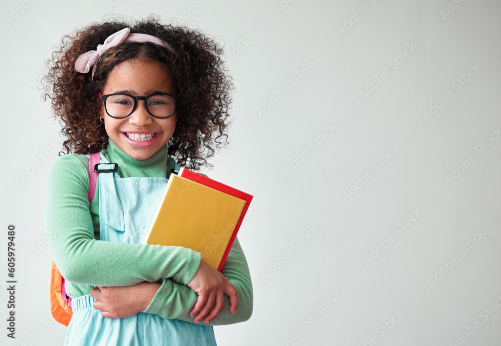 Obraz premium Education, smart and portrait a child with books for knowledge, reading and studying in a studio. Happy, smile and young girl kid student with glasses isolated by a white background with mockup space