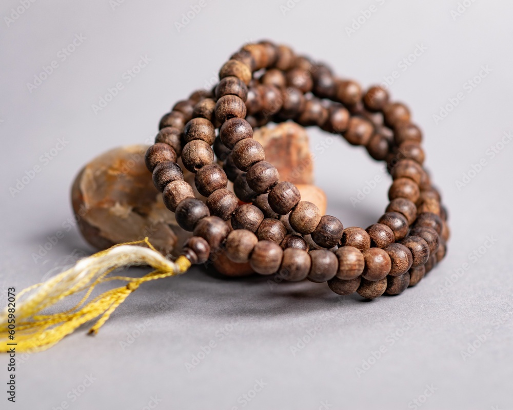 Obraz premium Wooden Mala prayer beads leaning on a stone, isolated on a purple background