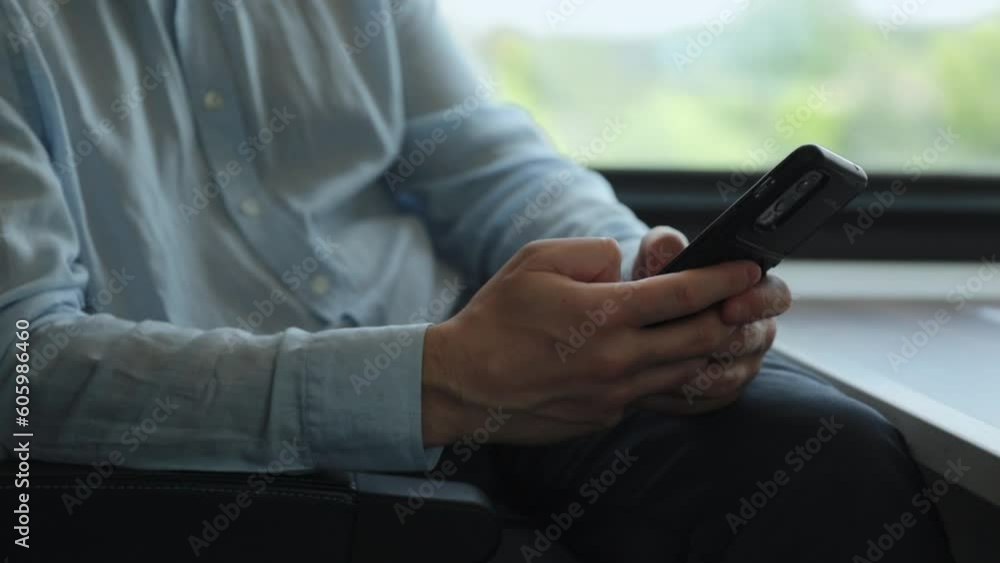 The phone is in the hands of a man businessman, on the train by the window. The concept of an entrepreneur's business trip The phone is in the hands of a man businessman, on the train by the window. The concept of an entrepreneur's business trip
