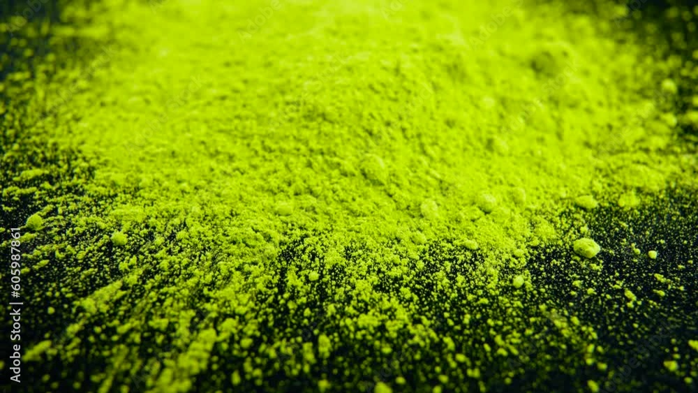 Close-up view of scattered matcha tea powder on a black surface
