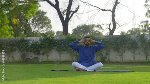 Young Indian man doing breathing exercise in a park photo