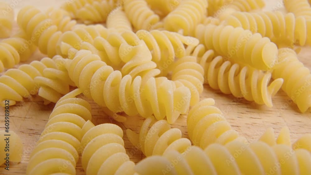 Closeup of a bunch of pasta poured on the wooden kitchen board surface Closeup of a bunch of pasta poured on the wooden kitchen board surface