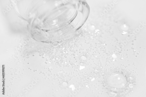 Transparent gel or liquid with bubbles flowing from the bottle onto the background