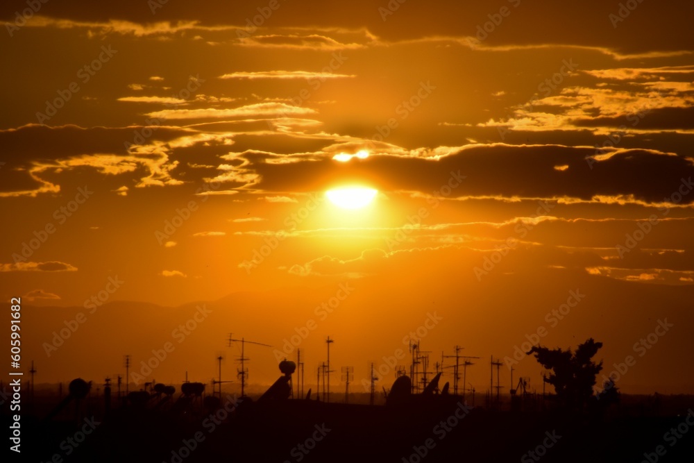 Closeup of sunset with antennas from houses beneath it