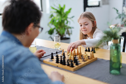 Friends girl child and adult mother play chess on the table.