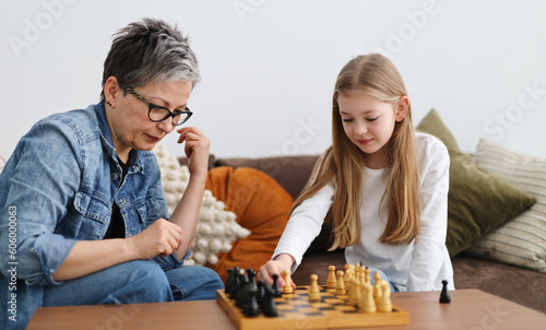 This is exactly my mature grandmother playing chess with her granddaughter child in a home interior.