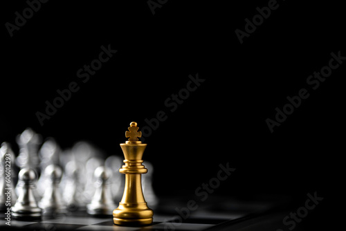Golden King chess standing in front of other chess on chess board.
