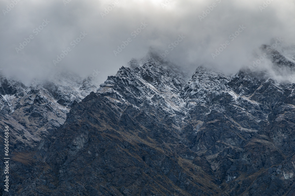 Rocky mountain peaks covered in snow on a foggy day in Queenstown, New Zealand
